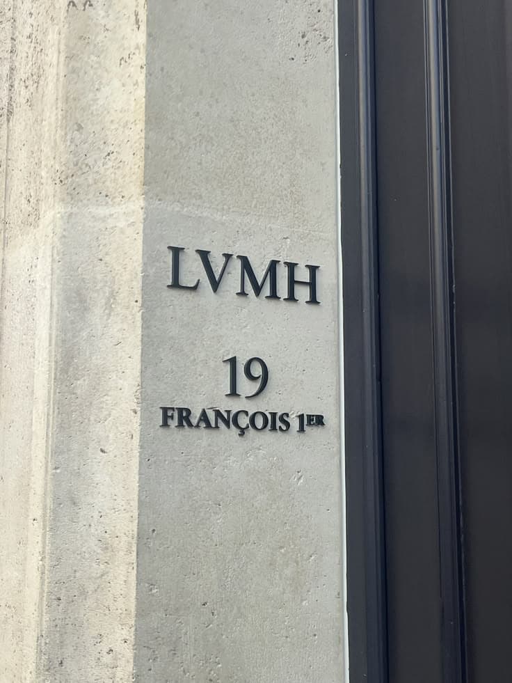 Табличка LVMH с адресом 19, François 1er на светлой каменной стене у тёмной двери
